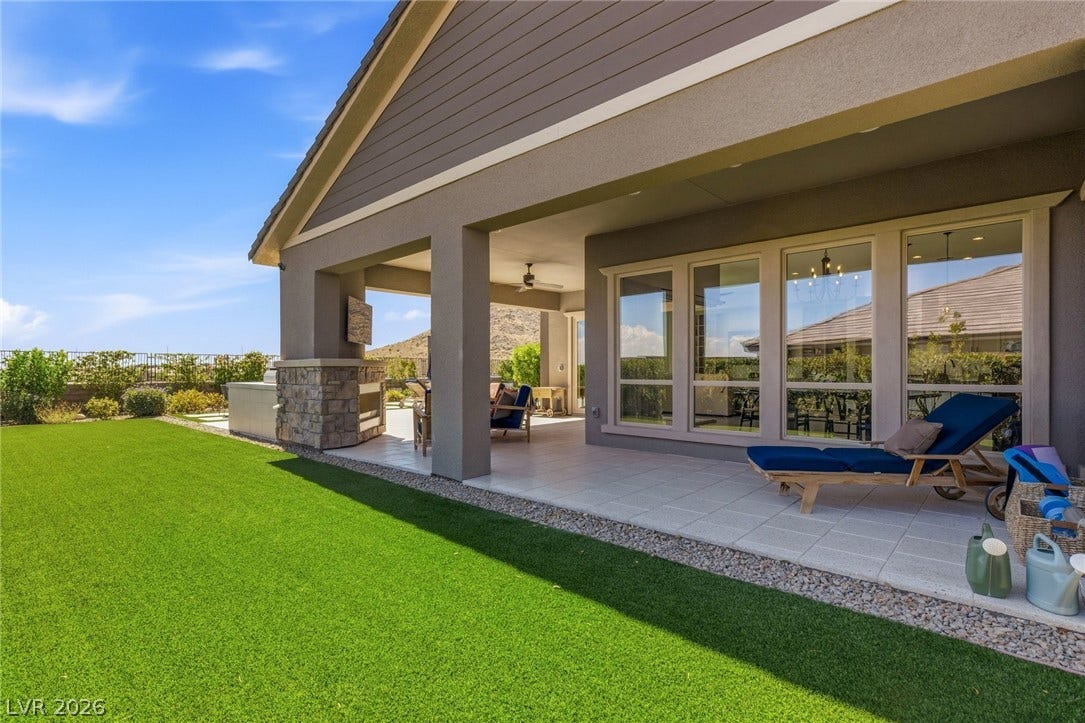 An inviting covered patio alongside an expansive turf area.