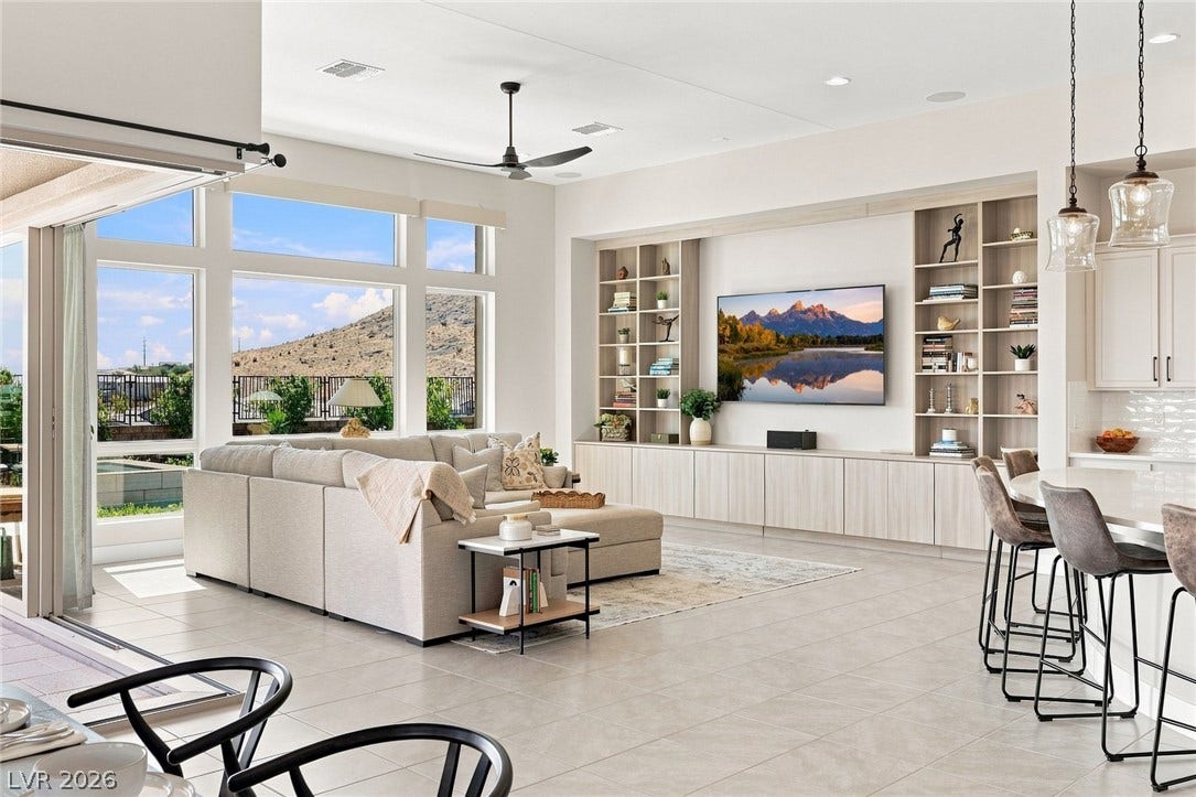 An open floorplan connects the living area with tall windows overlooking scenic mountains.