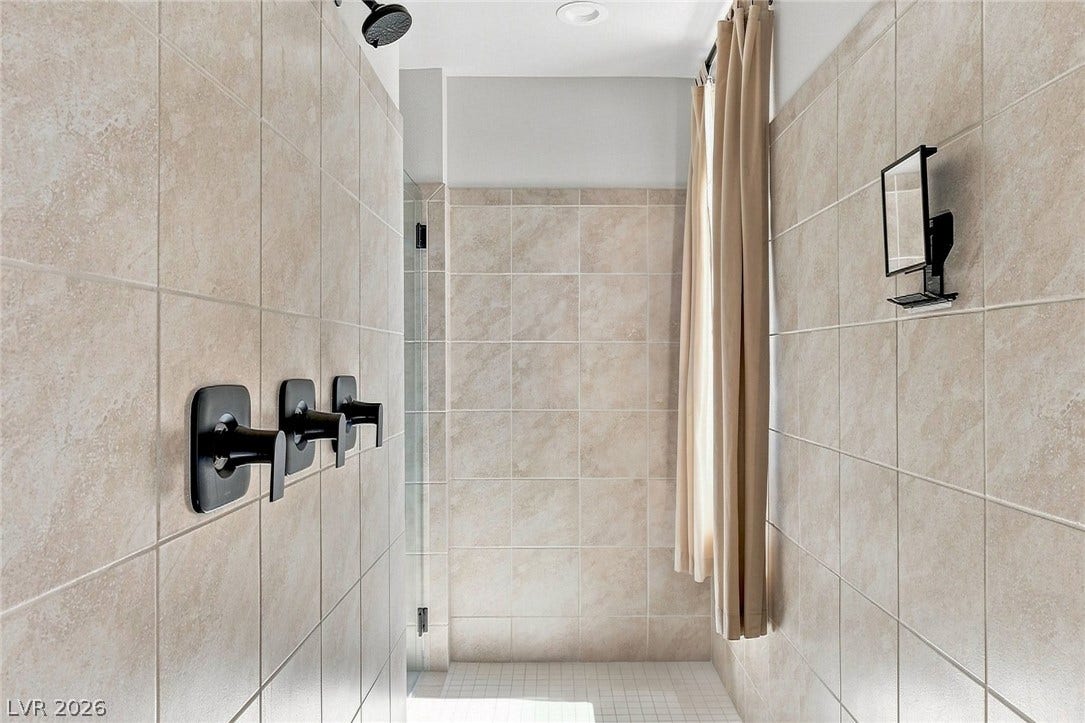 Spacious walk-in shower equipped with modern matte black fixtures.