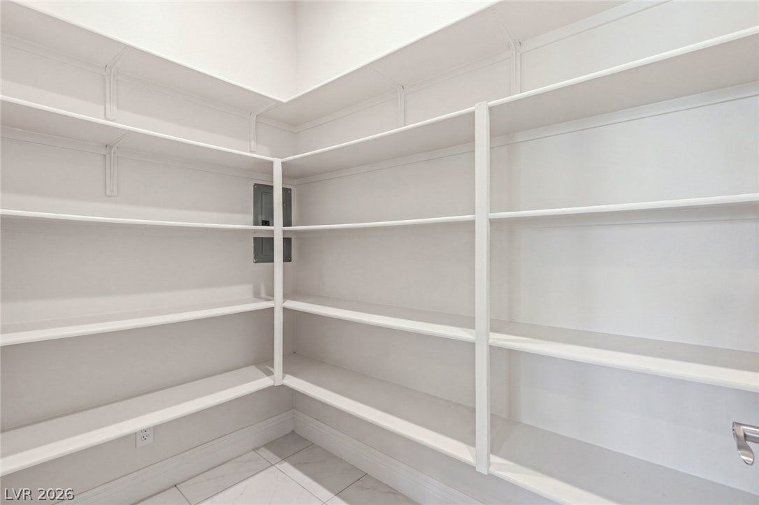 Floor-to-ceiling built-in shelving maximizes storage space in this tiled walk-in pantry.