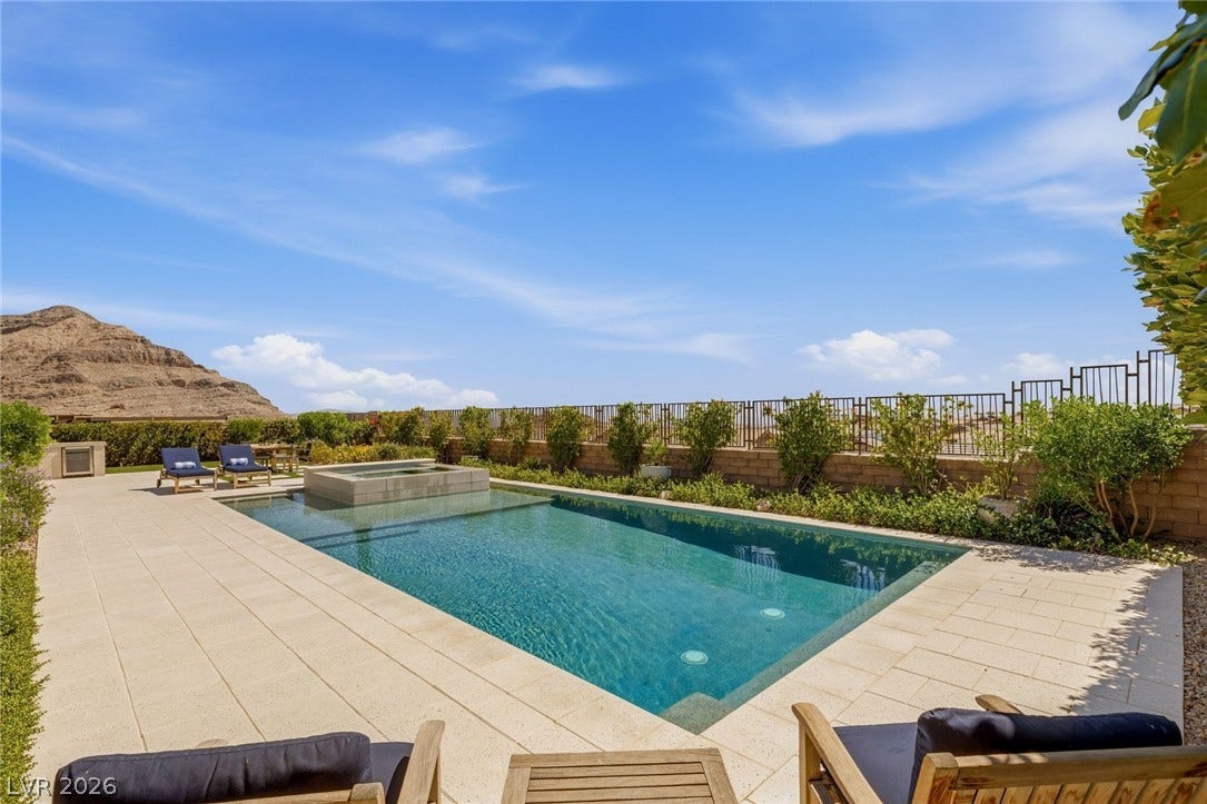 An inviting swimming pool and spa sit framed by mountain views