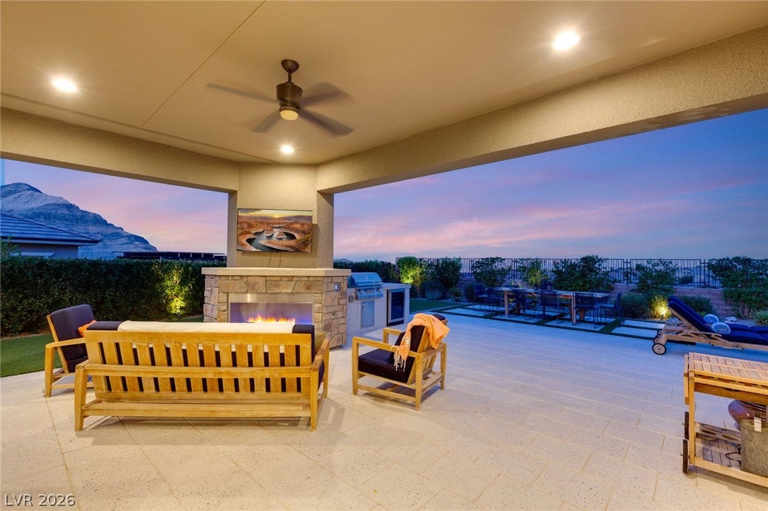 A spacious covered terrace frames majestic mountain vistas alongside a built-in stone fireplace.