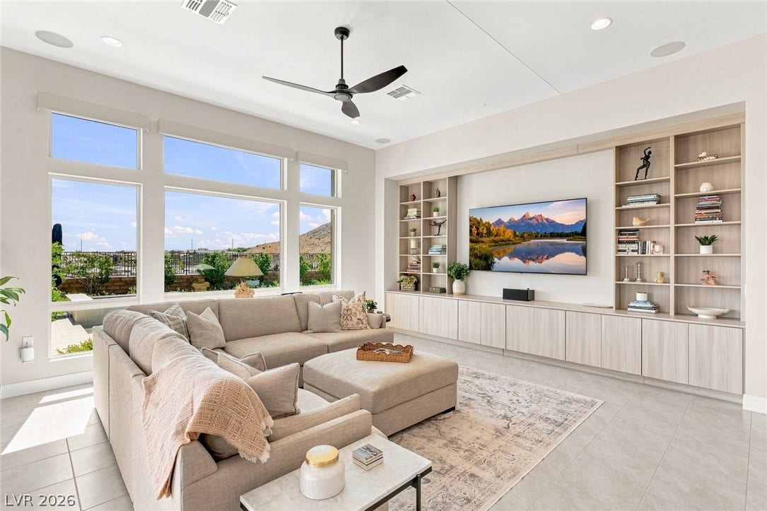 A spacious living area features custom built-in shelving, and large windows framing scenic views.