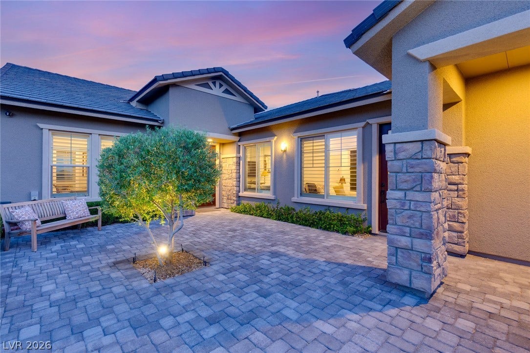 An inviting stone courtyard features elegant paved stones under a beautifully lit facade. Separate entrance to the secondary suite.