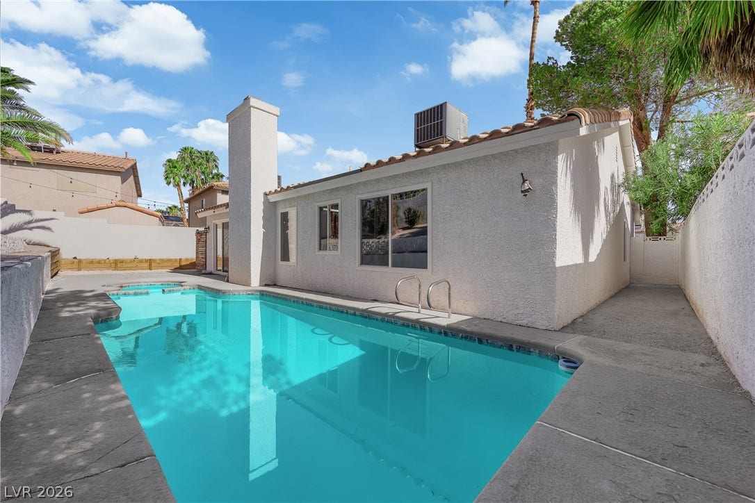 1433 Pathfinder Road, Henderson, NV 89014 An inviting backyard swimming pool is bordered by concrete decking alongside a stucco exterior.