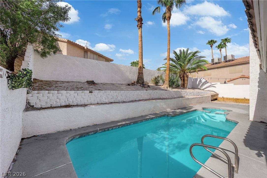 1433 Pathfinder Road, Henderson, NV 89014 A sparkling in-ground pool is framed by towering palms and terraced retaining walls.
