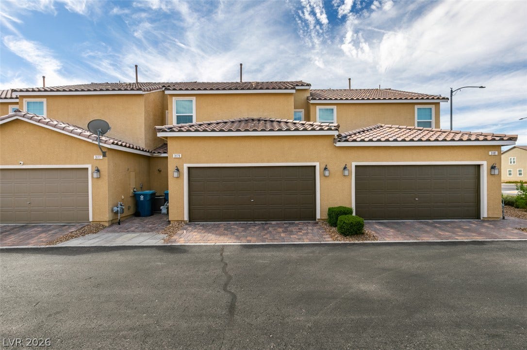 3179 Brynley Avenue, Henderson, NV 89044 Multi-car garage spaces front this multi-level stucco exterior featuring Spanish tile roofing.
