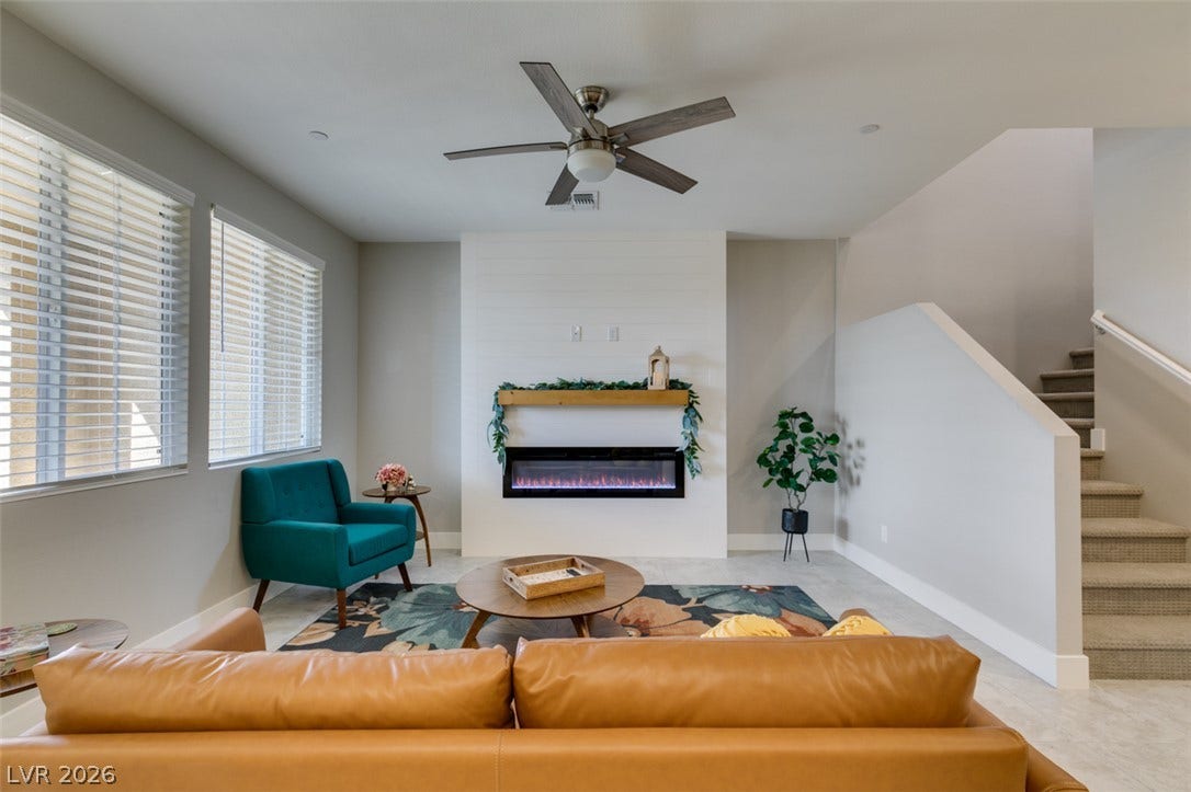 3179 Brynley Avenue, Henderson, NV 89044 An integrated electric fireplace centers the living space adjacent to a carpeted staircase.