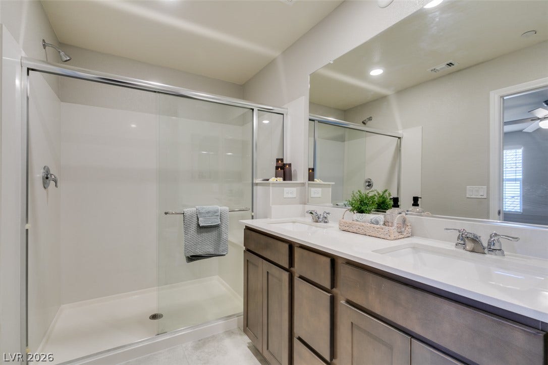 3179 Brynley Avenue, Henderson, NV 89044 Clean lines and a double vanity define this contemporary bathroom space with a glass shower enclosure.