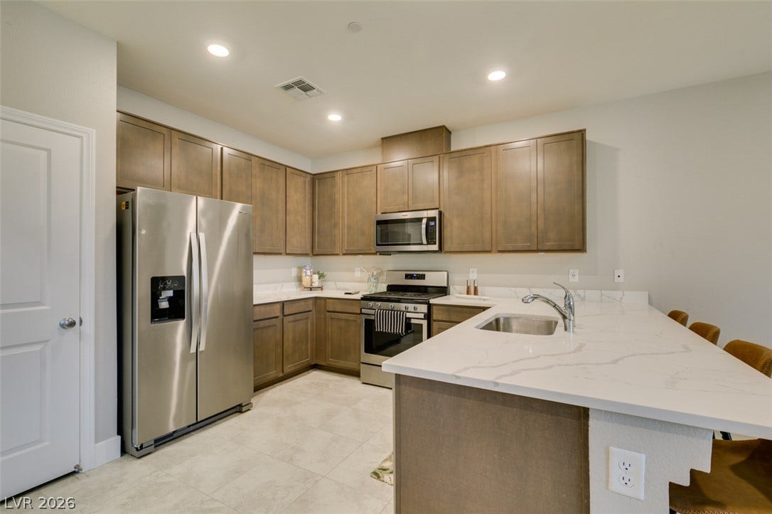 3179 Brynley Avenue, Henderson, NV 89044 Recessed lighting illuminates quartz countertops, flat-panel cabinetry, and stainless steel appliances in this functional layout.