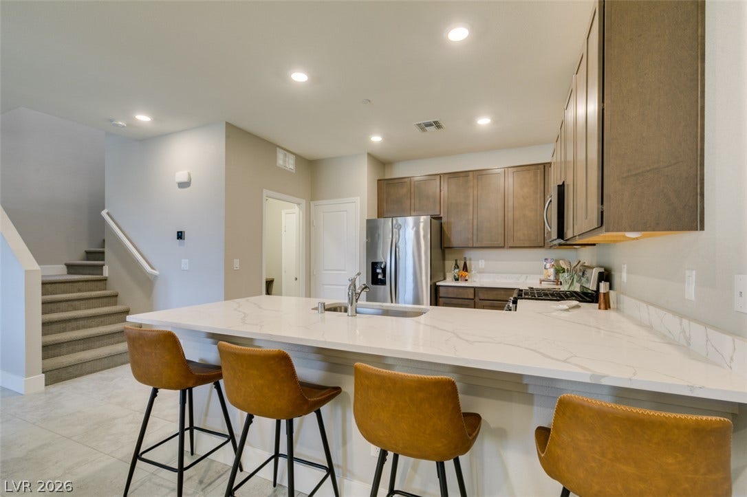 3179 Brynley Avenue, Henderson, NV 89044 Granite counters and recessed lighting elevate this modern kitchen featuring a breakfast bar.