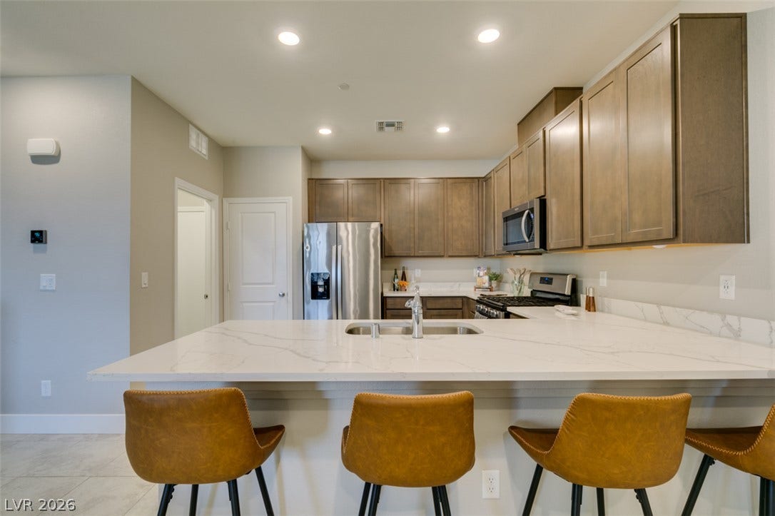 3179 Brynley Avenue, Henderson, NV 89044 Streamlined cabinetry and sleek stone countertops define this modern kitchen workspace.