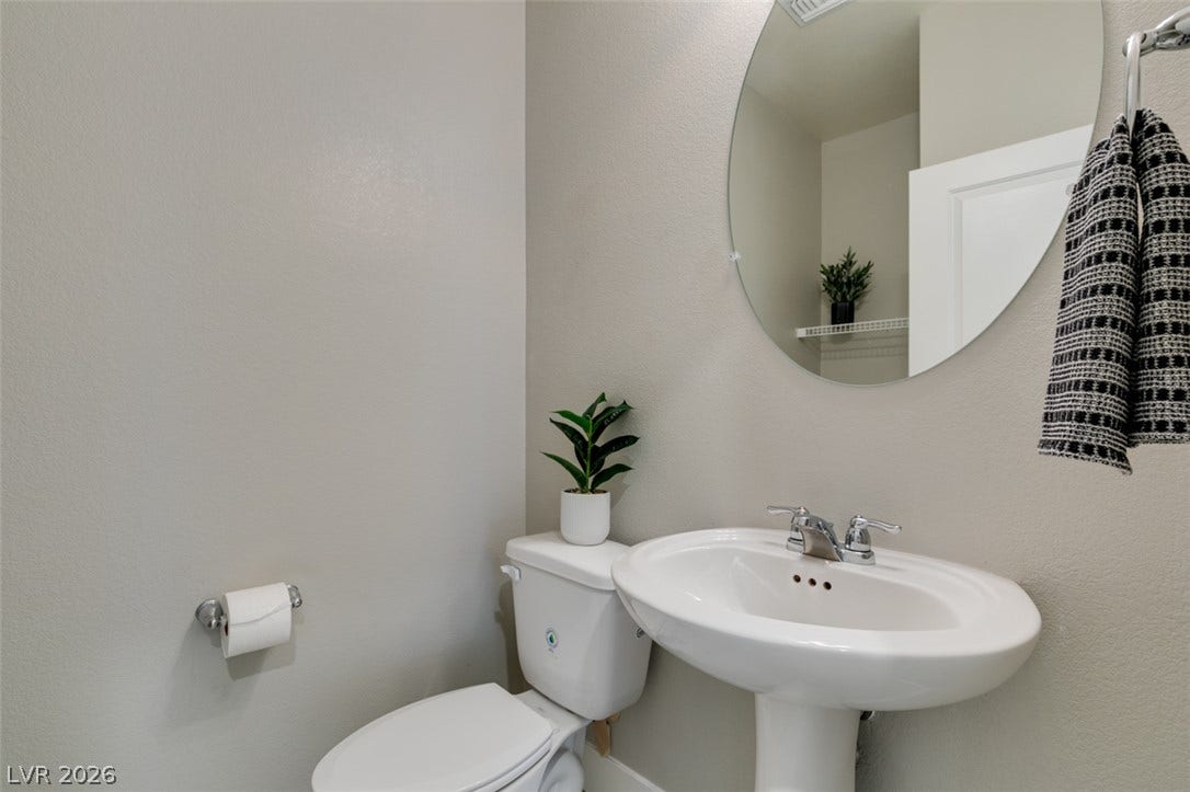 3179 Brynley Avenue, Henderson, NV 89044 A classic pedestal sink pairs with a circular mirror in this functional powder room.