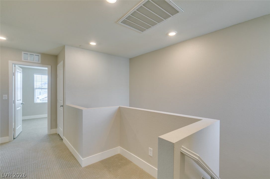 3179 Brynley Avenue, Henderson, NV 89044 Recessed lighting illuminates a carpeted upstairs hallway leading past a staircase with half-walls.