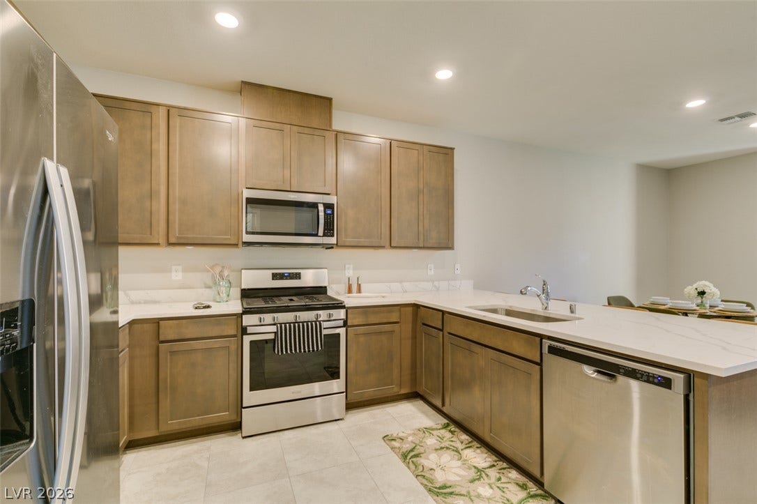 3179 Brynley Avenue, Henderson, NV 89044 Recessed lighting illuminates wood cabinetry and modern stone countertops in this open kitchen layout.