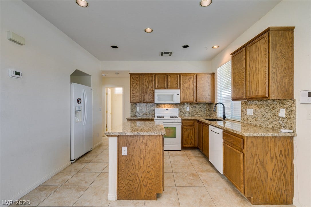 Rich oak cabinetry and durable granite countertops anchor this kitchen designed with a central island.