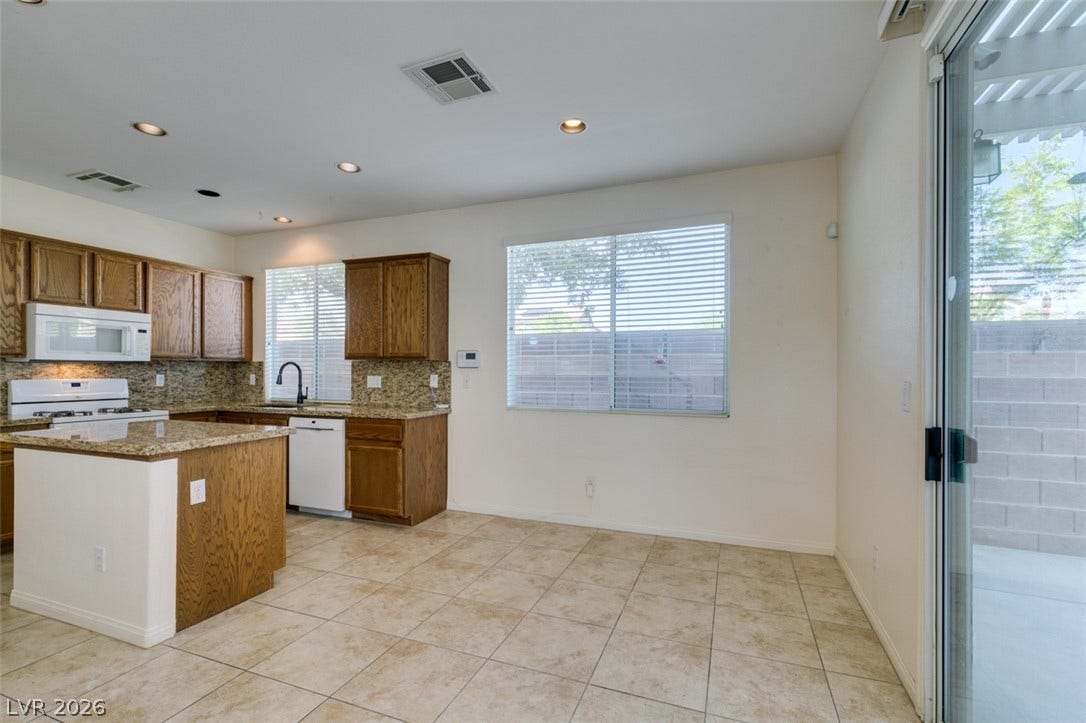 An open dining area adjacent to the kitchen features tile flooring and sliding glass doors.