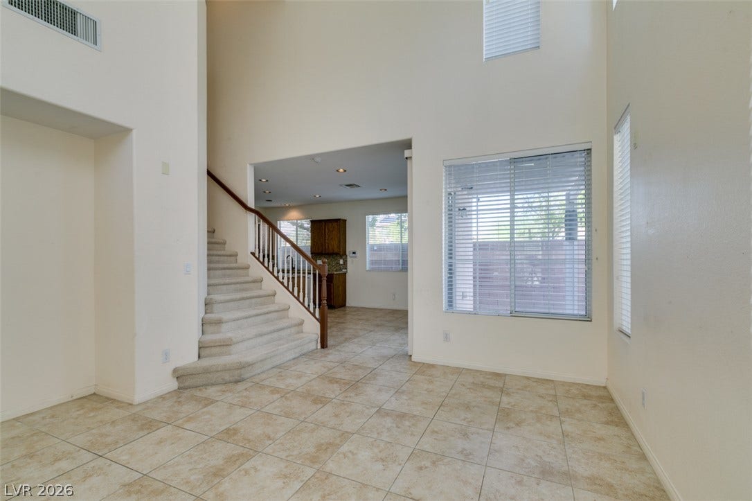 Soaring ceilings and neutral tile flooring define this airy open-concept living space.