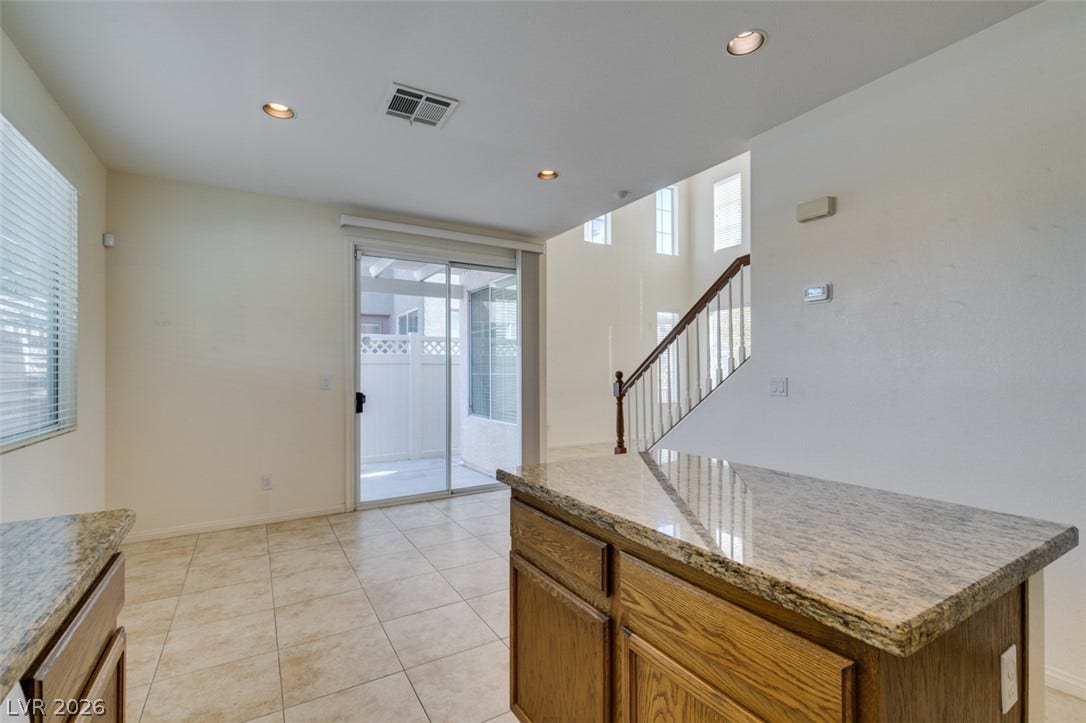 Gleaming stone countertops and ceramic tile flooring define this bright, open kitchen space.