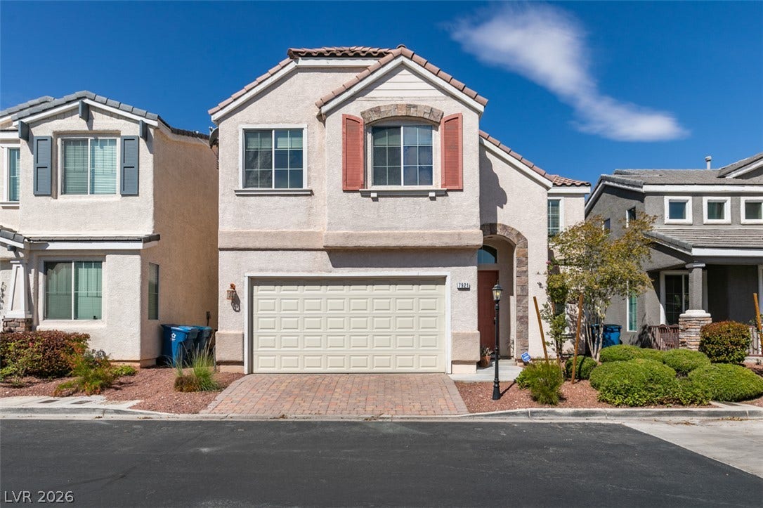 Tile roofing and decorative window shutters enhance this multi-level stucco home with a paved driveway.