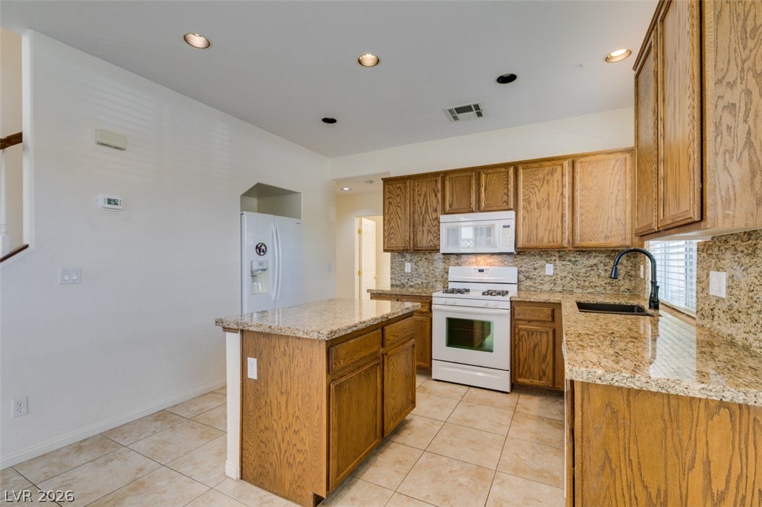 Rich oak cabinetry and durable granite countertops anchor this kitchen designed with a central island.