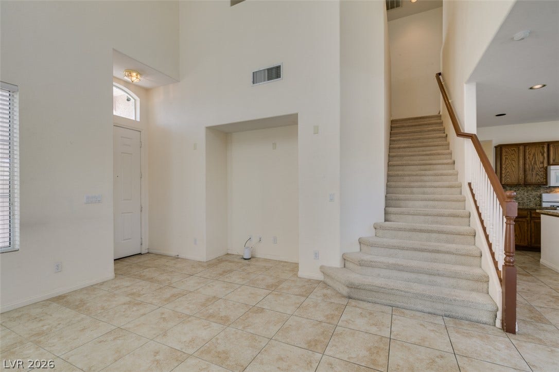 High ceilings and durable tile flooring define this airy entryway featuring a carpeted staircase.