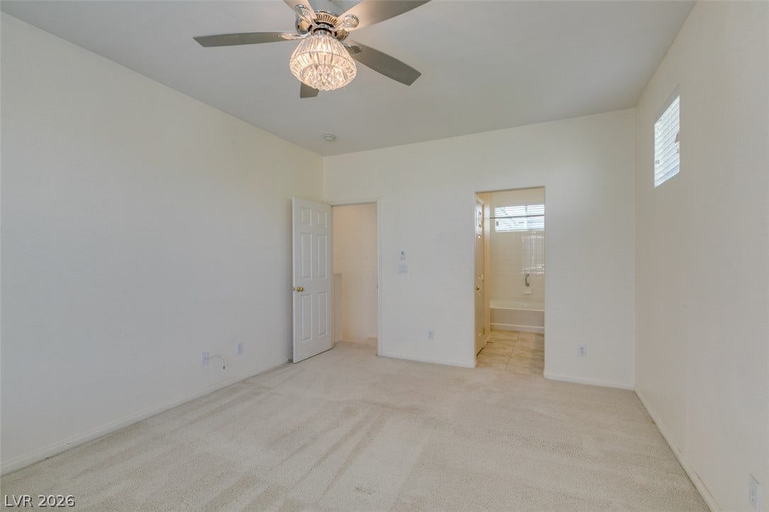 A spacious bedroom features soft wall-to-wall carpeting and connects directly to an en suite bathroom.
