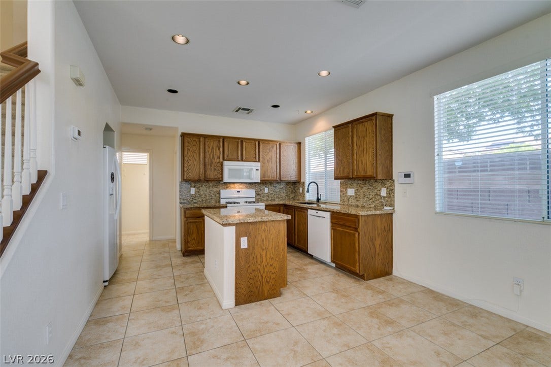 Warm wood cabinetry and granite countertops anchor this kitchen equipped with a central prep island.