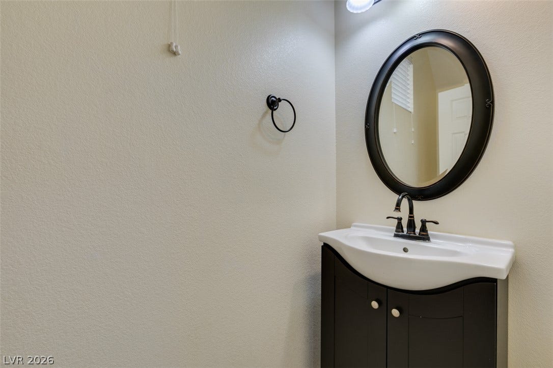 An oval dark-framed mirror pairs beautifully with a modern dark vanity in this powder room.