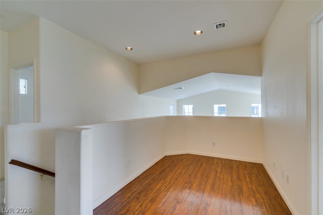 Warm wood flooring pairs beautifully with smooth gallery-style walls in this upper-level loft area.