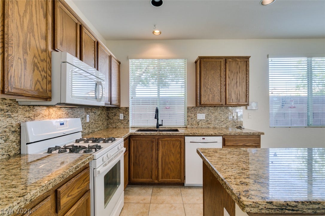 Rich oak cabinetry complements patterned stone countertops and tile flooring in this functional culinary space.