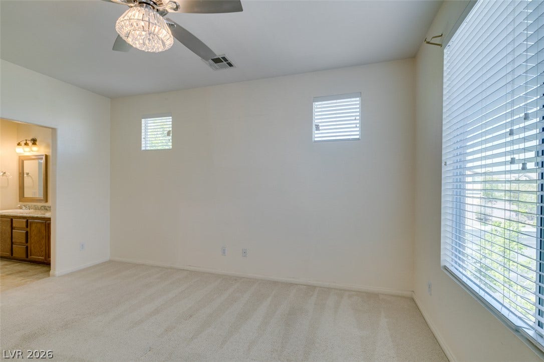 Plentiful natural light filters through multiple windows onto the soft carpeted flooring.