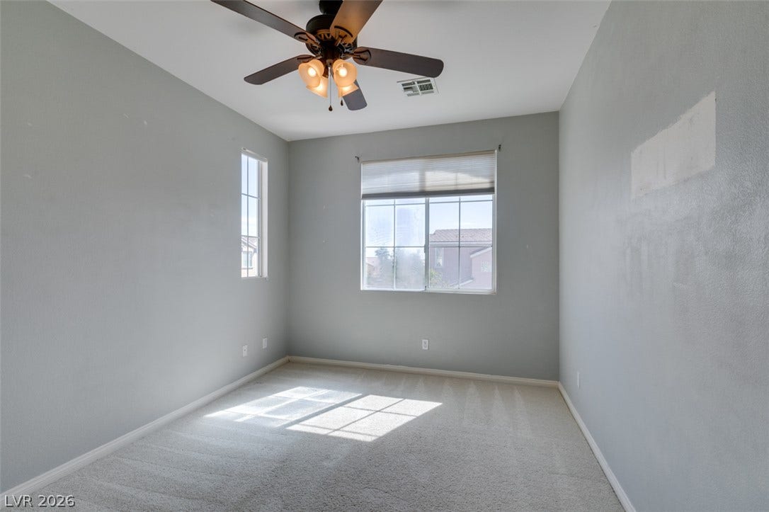 Plentiful natural light streams across the carpeted floor through dual dual-pane windows.