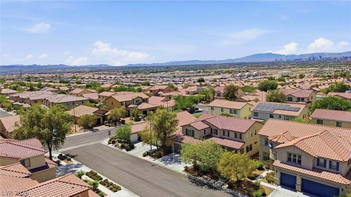 2607 Fading Night Court, Las Vegas, NV 89142 An aerial perspective showcases a neighborhood of tile-roofed homes under a clear desert sky.