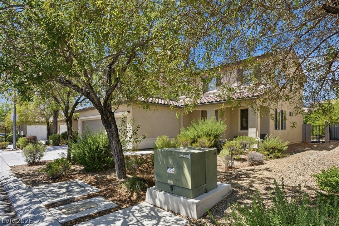2607 Fading Night Court, Las Vegas, NV 89142 Mature trees shade a classic stucco exterior with a tile roof and integrated garage.