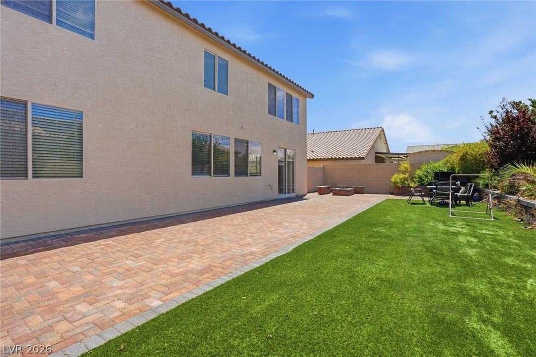 2607 Fading Night Court, Las Vegas, NV 89142 A spacious brick paver patio extends alongside a manicured green lawn under blue skies.