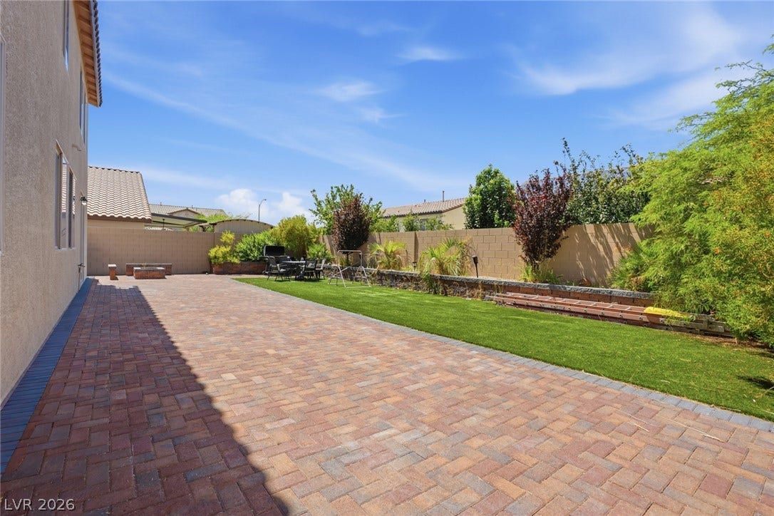 2607 Fading Night Court, Las Vegas, NV 89142 An expansive paved patio borders a level lawn and perimeter landscaping under blue skies.
