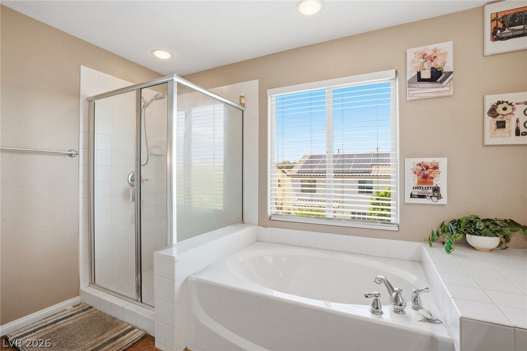 2607 Fading Night Court, Las Vegas, NV 89142 A deep soaking tub sits adjacent to a glass-enclosed shower stall under recessed lighting.
