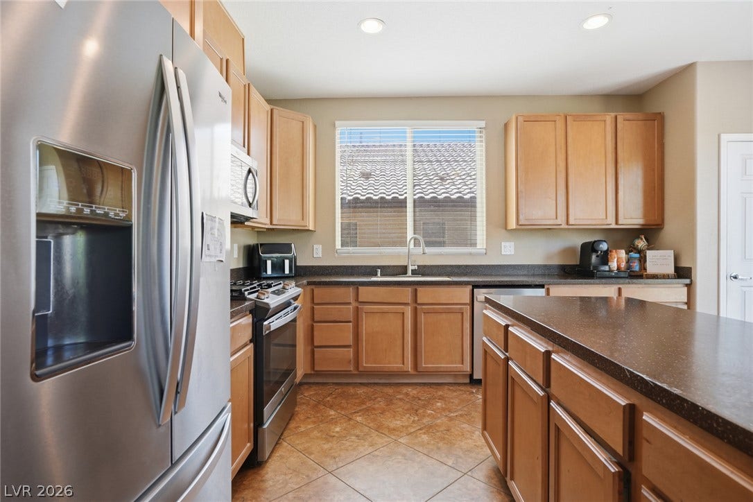 2607 Fading Night Court, Las Vegas, NV 89142 Gleaming tile flooring and matching wood cabinetry define this functional kitchen space with stone counters.