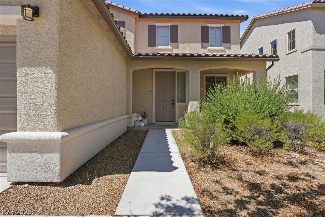 2607 Fading Night Court, Las Vegas, NV 89142 A concrete walkway leads to the covered front entry of this two-story stucco home.