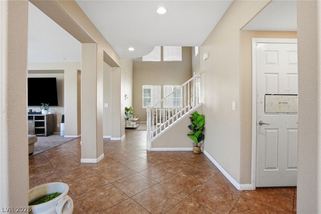 2607 Fading Night Court, Las Vegas, NV 89142 Tiled flooring transitions into an open layout featuring high ceilings and a central staircase.