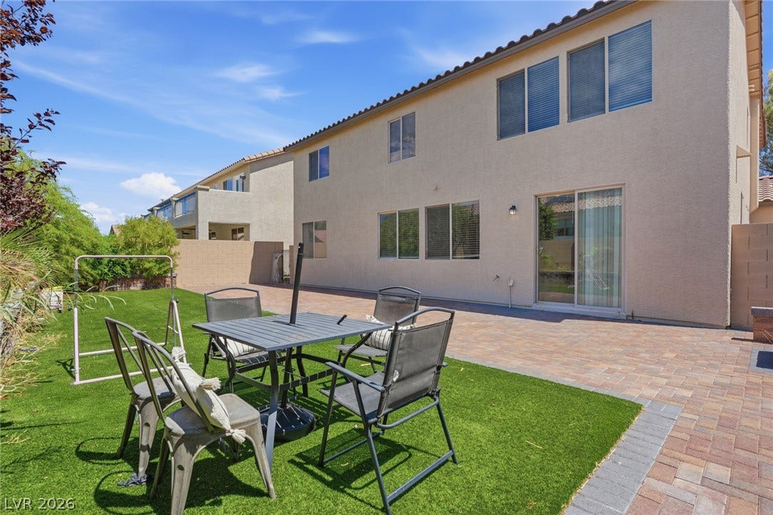 2607 Fading Night Court, Las Vegas, NV 89142 An expansive paved patio and manicured lawn area border the rear stucco exterior.