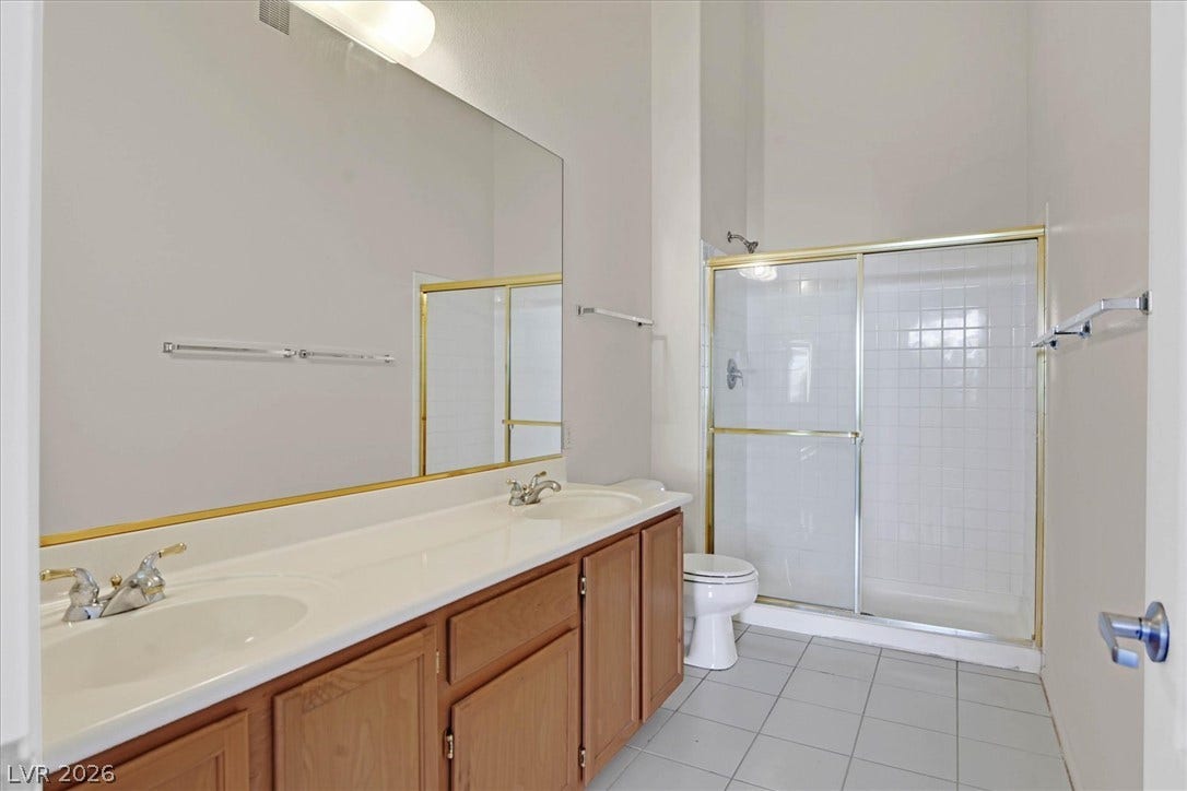 700 Carnegie Street, #2924, Henderson, NV 89052 High ceilings and a dual vanity with oak cabinets elevate this tiled bathroom design.