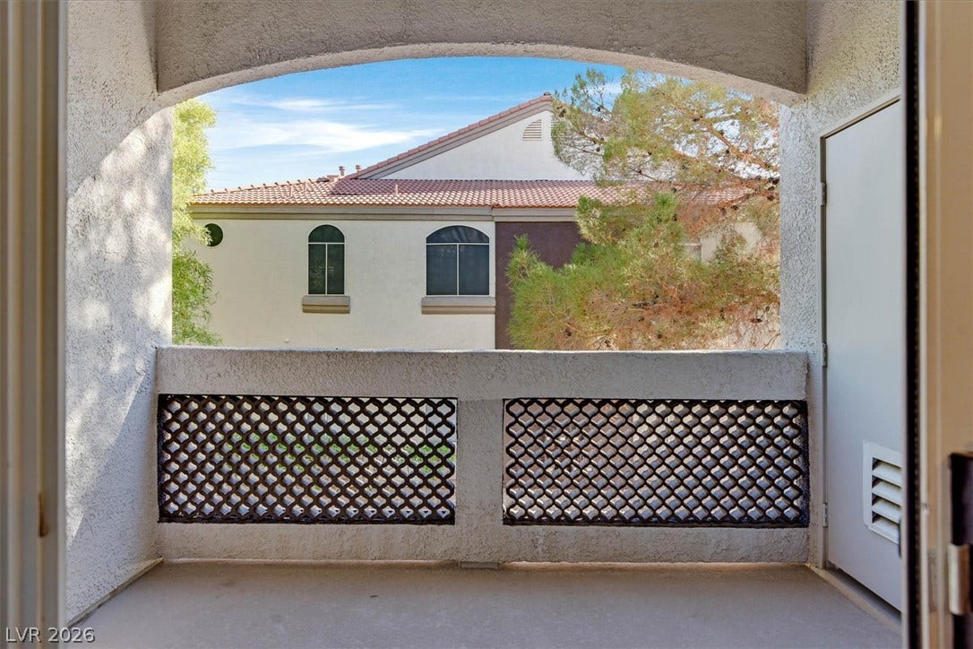 700 Carnegie Street, #2924, Henderson, NV 89052 An arched covered balcony features stucco finishes and a lattice railing overlooking mature trees.