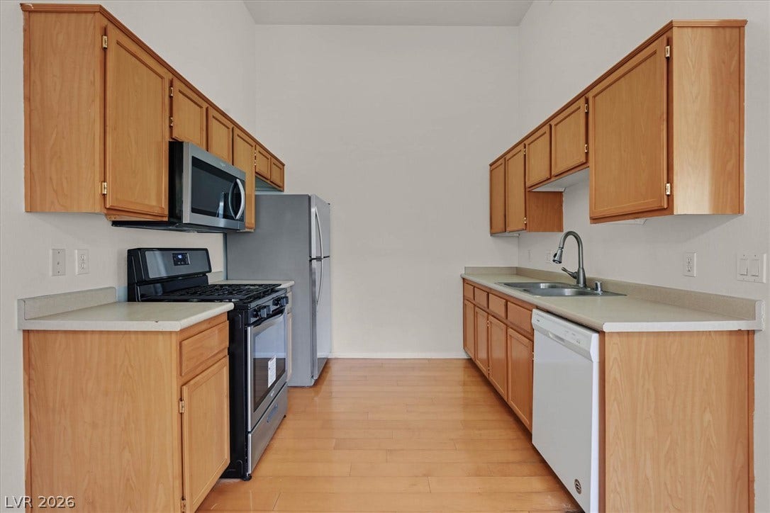 700 Carnegie Street, #2924, Henderson, NV 89052 Warm wood cabinetry and smooth laminate countertops line this functional galley kitchen.