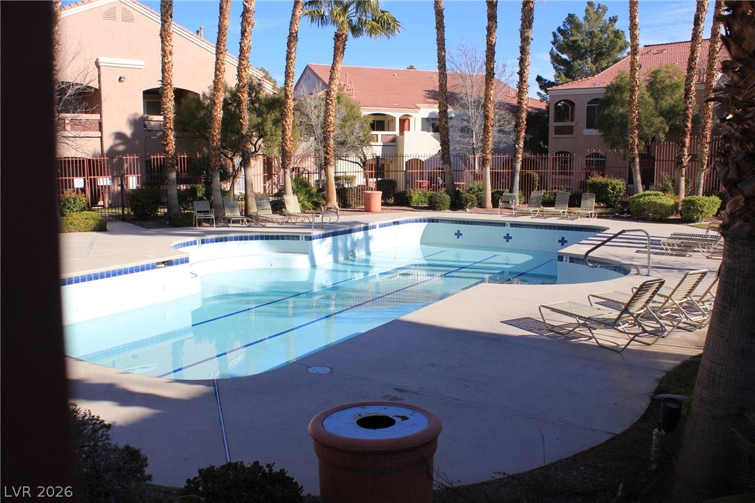 700 Carnegie Street, #2924, Henderson, NV 89052 Palm trees surround a clear swimming pool with concrete decking under sunny skies.