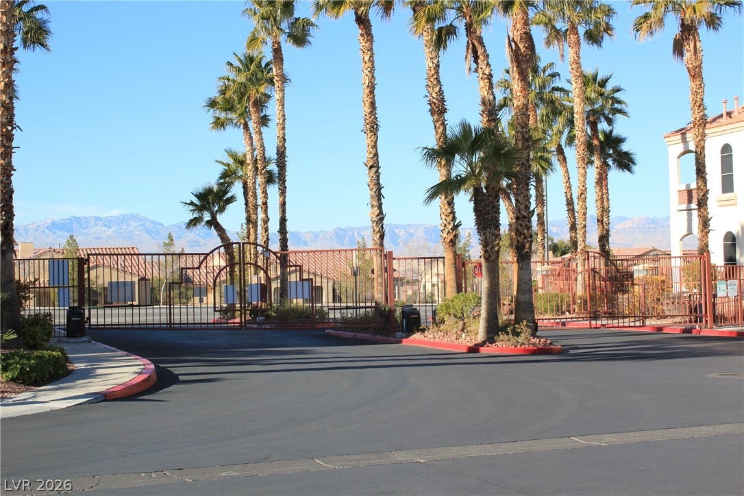 700 Carnegie Street, #2924, Henderson, NV 89052 Secure gated entry features paved roadways lined by towering palm trees against a mountain backdrop.