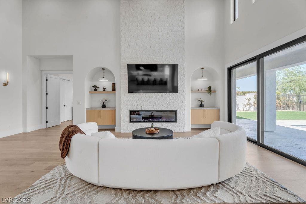 2690 Grassy Spring Place, Las Vegas, NV 89135 Double-height ceilings and a floor-to-ceiling stone fireplace frame this light-filled living area.