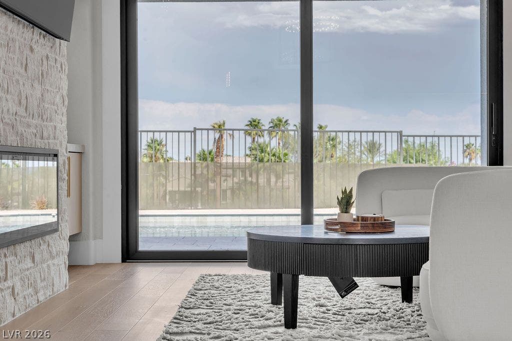 2690 Grassy Spring Place, Las Vegas, NV 89135 Massive sliding glass doors frame tranquil outdoor views alongside a textured stone fireplace surround.