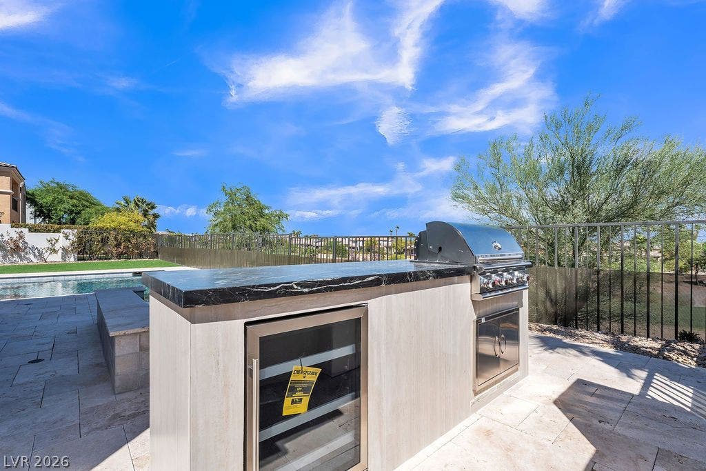 2690 Grassy Spring Place, Las Vegas, NV 89135 An outdoor kitchen features stone countertops alongside a built-in grill and beverage fridge.